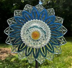 a glass sunflower sitting on top of a wooden stand in front of some grass