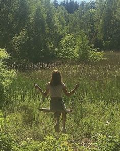 a girl swinging on a swing in the grass