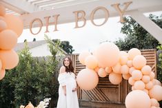 a woman standing in front of a bunch of balloons with the word oh boy on it