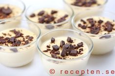 four desserts in small glass bowls with chocolate chips on top and cream filling the middle