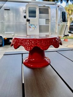 a red cake plate sitting on top of a wooden table next to a camper