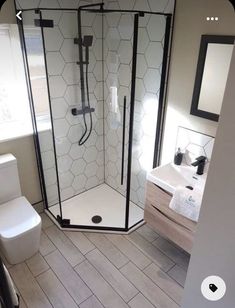 a white toilet sitting next to a shower in a bathroom on top of a hard wood floor