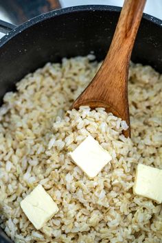 rice and butter are being cooked in a pan with a wooden spoon on the side