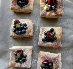 four pieces of bread topped with fruit and powdered sugar on top of a baking sheet