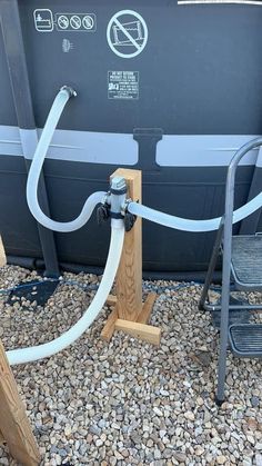 two metal hoses connected to the back of a gray and black trash can on gravel