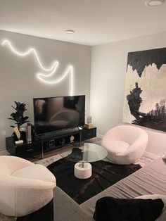 a living room with two white chairs and a black table in front of a tv