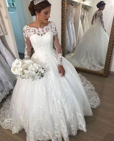 a woman in a white wedding dress looking at her reflection in a mirror with flowers on it