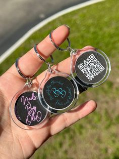 someone is holding three keychains with qr code on them in their hand