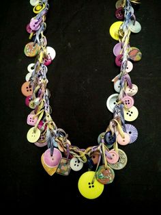 a multi - stranded necklace with buttons and chains on a black background is shown