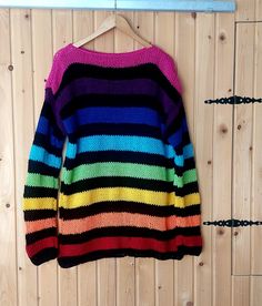 a multicolored sweater hanging on a wooden wall