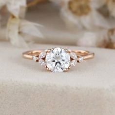 a rose gold engagement ring with three stones on the band and an oval center stone