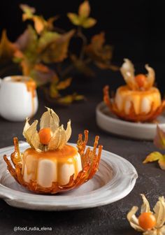 two small desserts on plates with leaves and flowers in the middle one is topped with caramel sauce