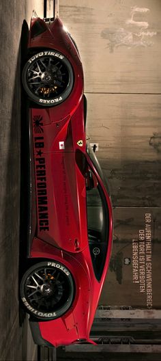 a red sports car parked next to a wall