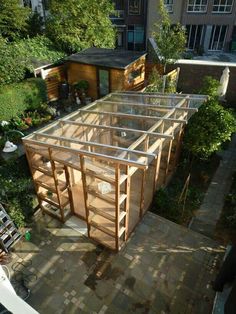 an overhead view of a building made out of wooden pallets and glass panels, surrounded by greenery