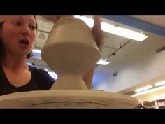 a woman is making a vase out of clay