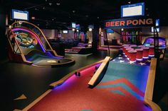 an indoor bowling game room with neon lights and colorful rugs on the floor, as well as video screens