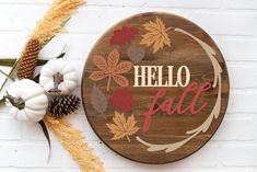 a wooden sign that says hello fall with leaves and acorns next to it