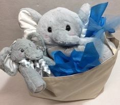 an elephant stuffed animal in a basket with blue ribbon on the top and another stuffed animal sitting next to it