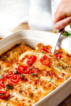 a person is cutting into a casserole dish with cheese and red bell peppers