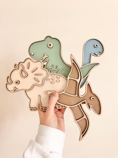 a person holding up a wooden cutout of different types of dinosaurs and sea creatures