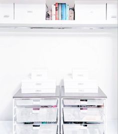 the shelves are full of books and magazines in this white room with two bins filled with files