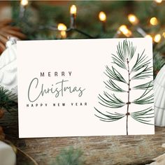 a christmas card sitting on top of a wooden table next to pine cones and candles