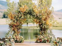 an outdoor ceremony setup with flowers and greenery on the grass, near a lake