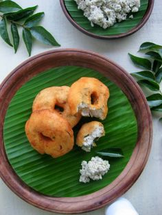 two donuts are sitting on a plate with some flowers in the back ground and green leaves surrounding them