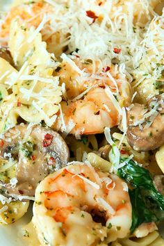 pasta with shrimp, mushrooms, spinach and parmesan cheese in a white bowl