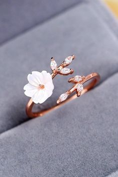 a close up of a ring on a box with a flower and leaves design in it