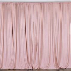 a cat is sitting on the floor in front of a pink curtain