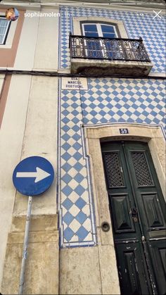 a blue and white tiled building with an arrow pointing to the right on a street sign