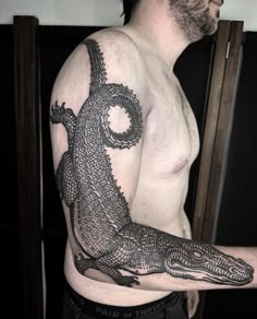 a man with a tattoo on his arm holding an alligator in the palm of his hand