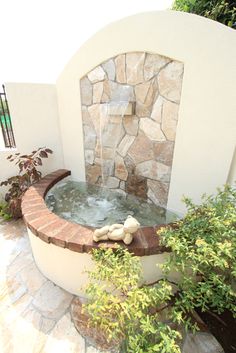 an outdoor fountain surrounded by plants and rocks