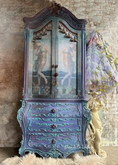 an old dresser with paintings on it next to a stuffed animal