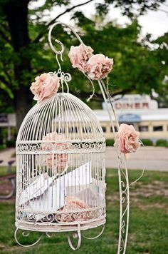 a white birdcage with pink roses hanging from it