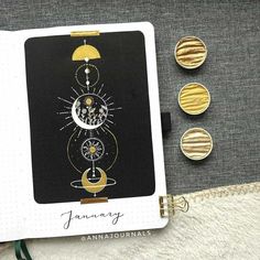 an open notebook with three different designs on it next to some gold and silver buttons