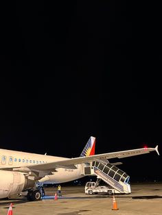 an airplane parked on the tarmac at night with stairs leading up to it's door