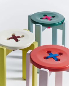 three different colored stools with holes in them and one has a cross on it