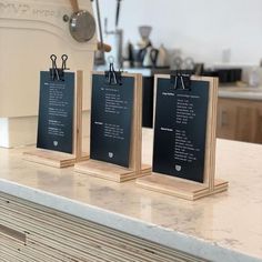 three small menus are sitting on top of a marble countertop in a kitchen