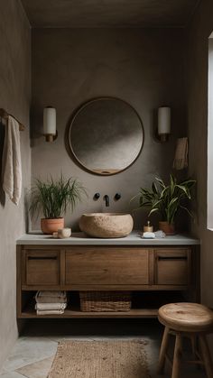 a bathroom with a round mirror above the sink and plants on the counter next to it