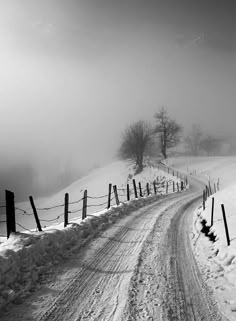 a road that is covered in snow next to a fence