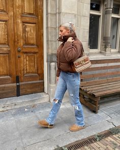 Brown short puffer jacket with destroyed jeans underneath en brown Uggs. Hair is up in a claw clip and wearing a brown bag from Guess. Light Brown Puffer Jacket Outfit, Brown Leather Puffer Jacket Outfit, Camel Puffer Jacket Outfit, Brown Puffer Coat Outfit, Tan Puffer Jacket Outfit, Corduroy Puffer Jacket Outfit, Leather Puffer Jacket Outfit, Tan Puffer Jacket