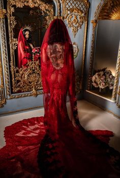 a woman in a red wedding dress standing next to a mirror with her back turned