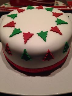 a white cake with green and red decorations on it's side sitting on a plate