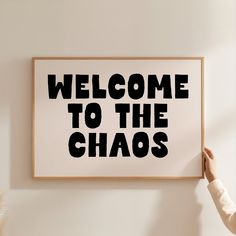 a person holding up a framed sign that says welcome to the chaoss on it