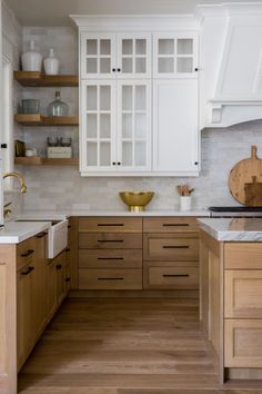 a kitchen with white cabinets and wood floors in the center is featured on this video