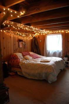 a bed sitting in a bedroom next to a window with lights on the wall above it