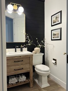 a white toilet sitting next to a wooden cabinet in a bathroom under a vanity mirror