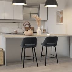 two black chairs sitting in front of a kitchen island